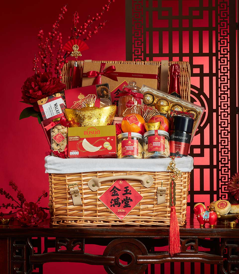 Luxury wicker gift basket with Chinese New Year treats, champagne, and gold accents on red background