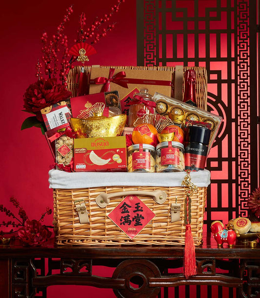 Luxury wicker gift basket with Chinese New Year treats, champagne, and gold accents on red background