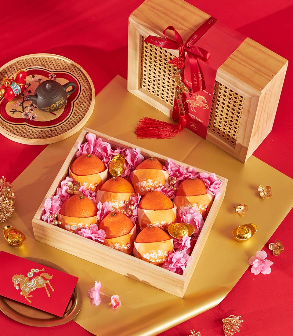 Premium mandarin orange gift box with gold coins and pink flowers on red and gold Chinese New Year background