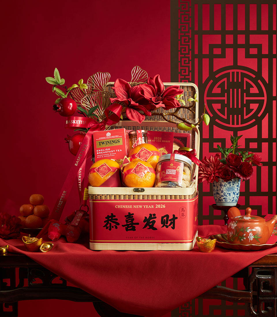 Red Chinese New Year gift basket with mandarin oranges, English tea, almond cookies, and gold ginkgo leaf accents for the