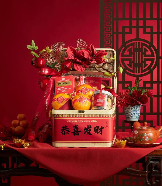 Red Chinese New Year gift basket with mandarin oranges, English tea, almond cookies, and gold ginkgo leaf accents for the