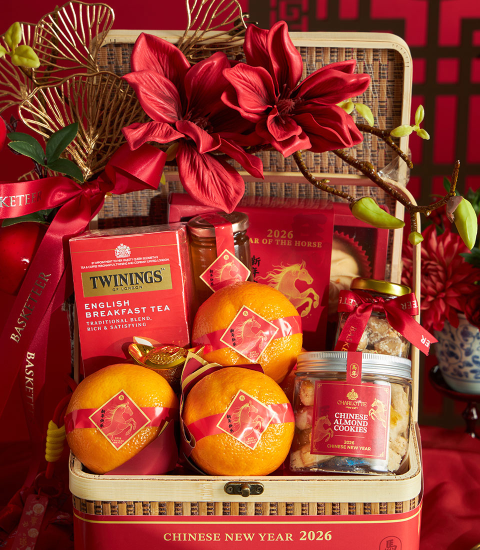 Red and gold Chinese New Year gift basket with mandarin oranges, Twinings tea, honey, almond cookies, and festive decorations