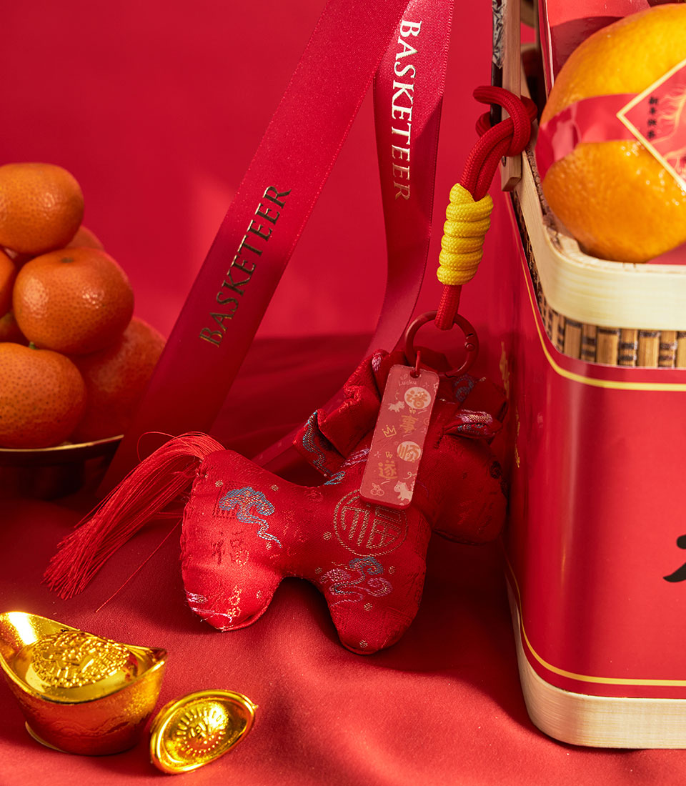 Chinese New Year mandarin orange and gourmet gift basket with gold ingots, red fabric charm, and festive red ribbon on rich