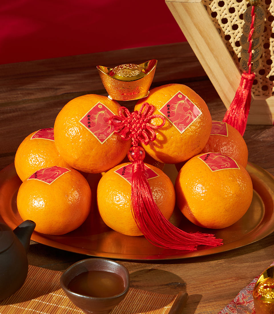 Mandarin oranges with red fortune stickers and golden tray for Chinese New Year gift hamper, styled with tea and lucky