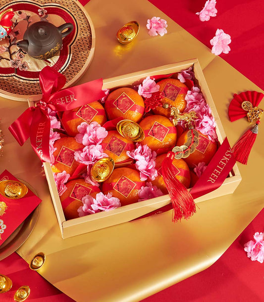 Premium mandarin orange gift box with red ribbons, gold accents, and cherry blossoms for Chinese New Year