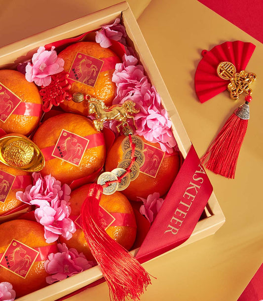 Premium mandarin orange gift box with red silk ribbons, gold horse charm, and Chinese New Year auspicious ornaments