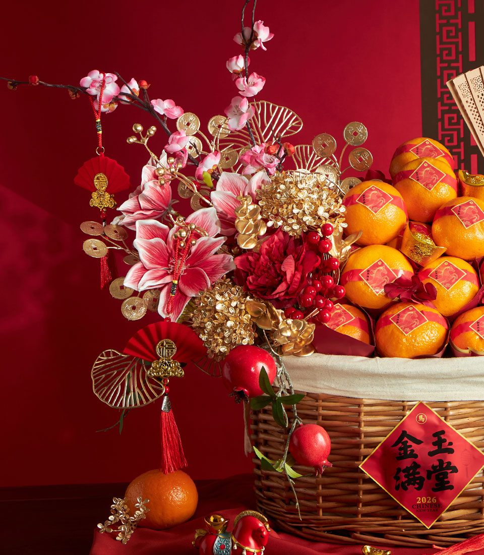 Festive Chinese New Year mandarin orange gift basket with red ribbons, symbolic flowers, gold coins, and bamboo fan on red