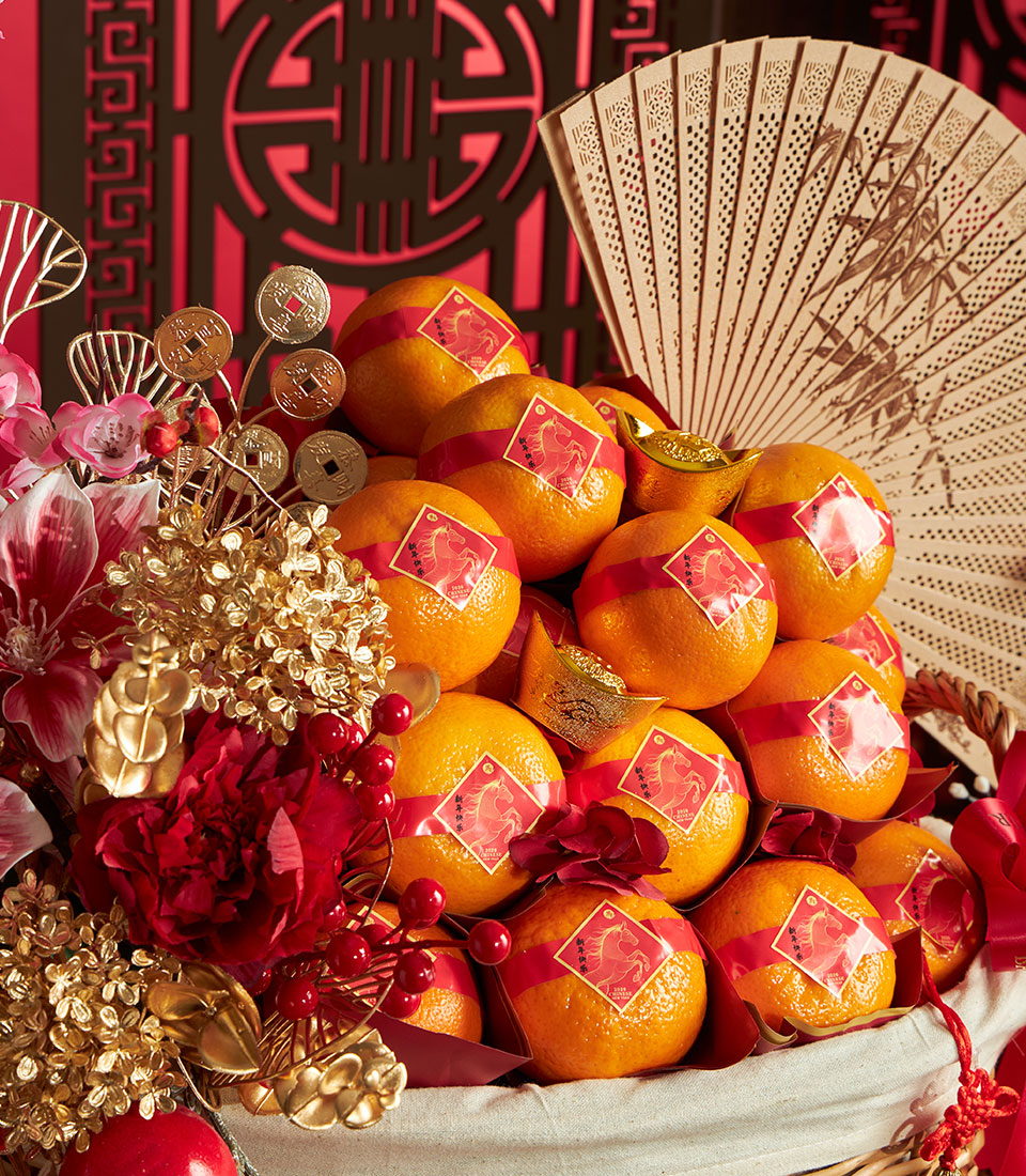 Festive Chinese New Year mandarin orange basket with bamboo fan, gold ingots, and lucky red ribbons