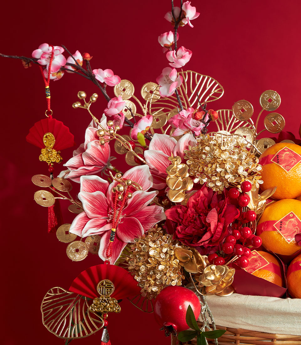 Vibrant Chinese New Year mandarin orange basket with fresh pomegranates, artificial florals, bamboo fan, and traditional