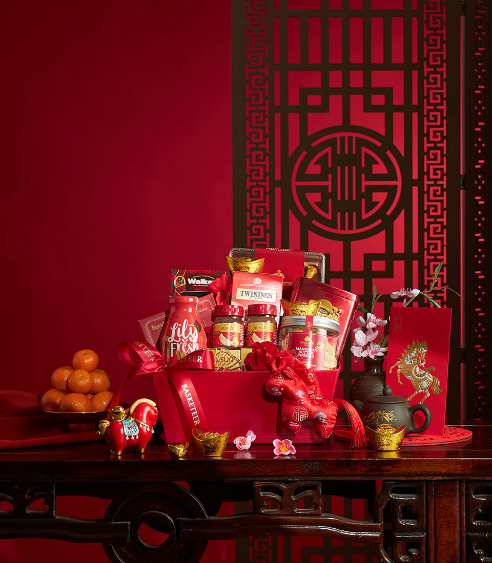 Chinese New Year luxury gift basket with gourmet chocolates, preserves, tea, and shortbread on dark wood table