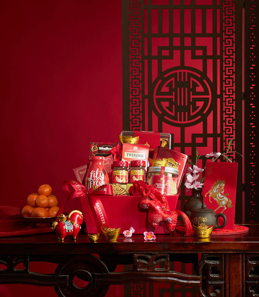 Chinese New Year luxury gift basket with gourmet chocolates, preserves, tea, and shortbread on dark wood table