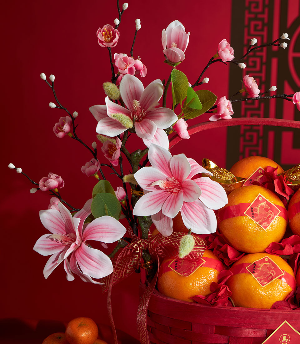 Red mandarin orange gift basket with artificial magnolia flowers and gold accents for Chinese New Year