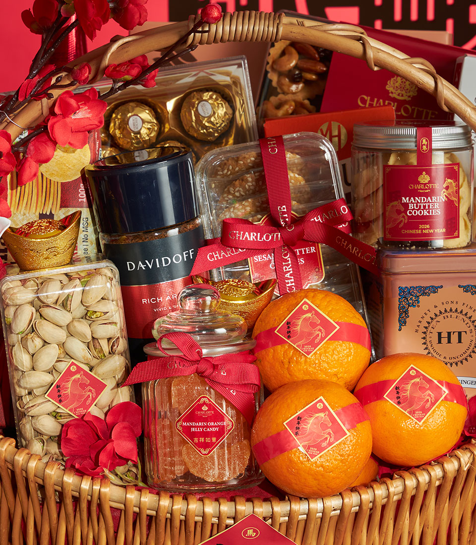 Woven wicker basket filled with mandarin orange jelly candy, butter cookies, pistachios, coffee, fresh oranges, and gold