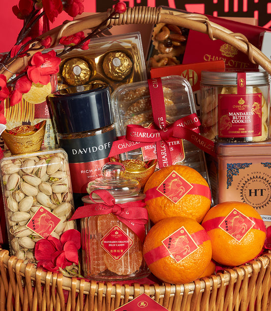 Woven wicker basket filled with mandarin orange jelly candy, butter cookies, pistachios, coffee, fresh oranges, and gold