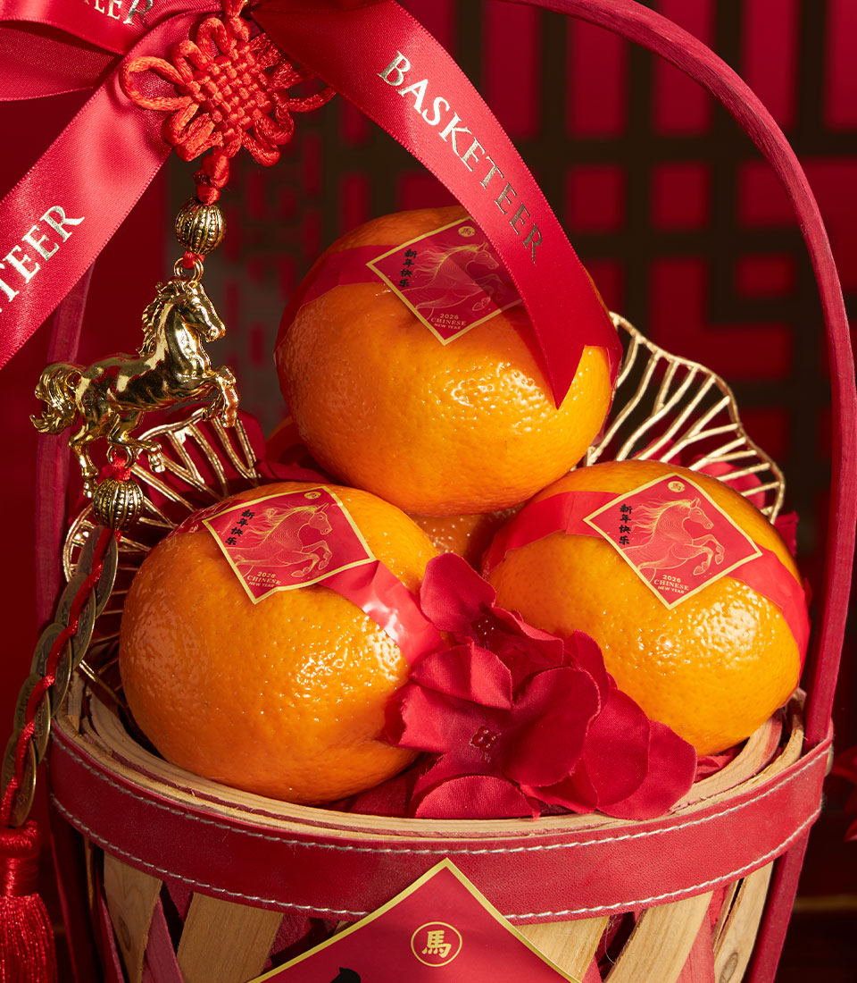 Festive red and gold gift basket with mandarin oranges, golden horse charm, and red ribbon for Chinese New Year celebrations