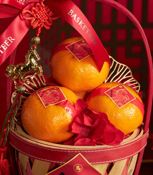 Festive red and gold gift basket with mandarin oranges, golden horse charm, and red ribbon for Chinese New Year celebrations