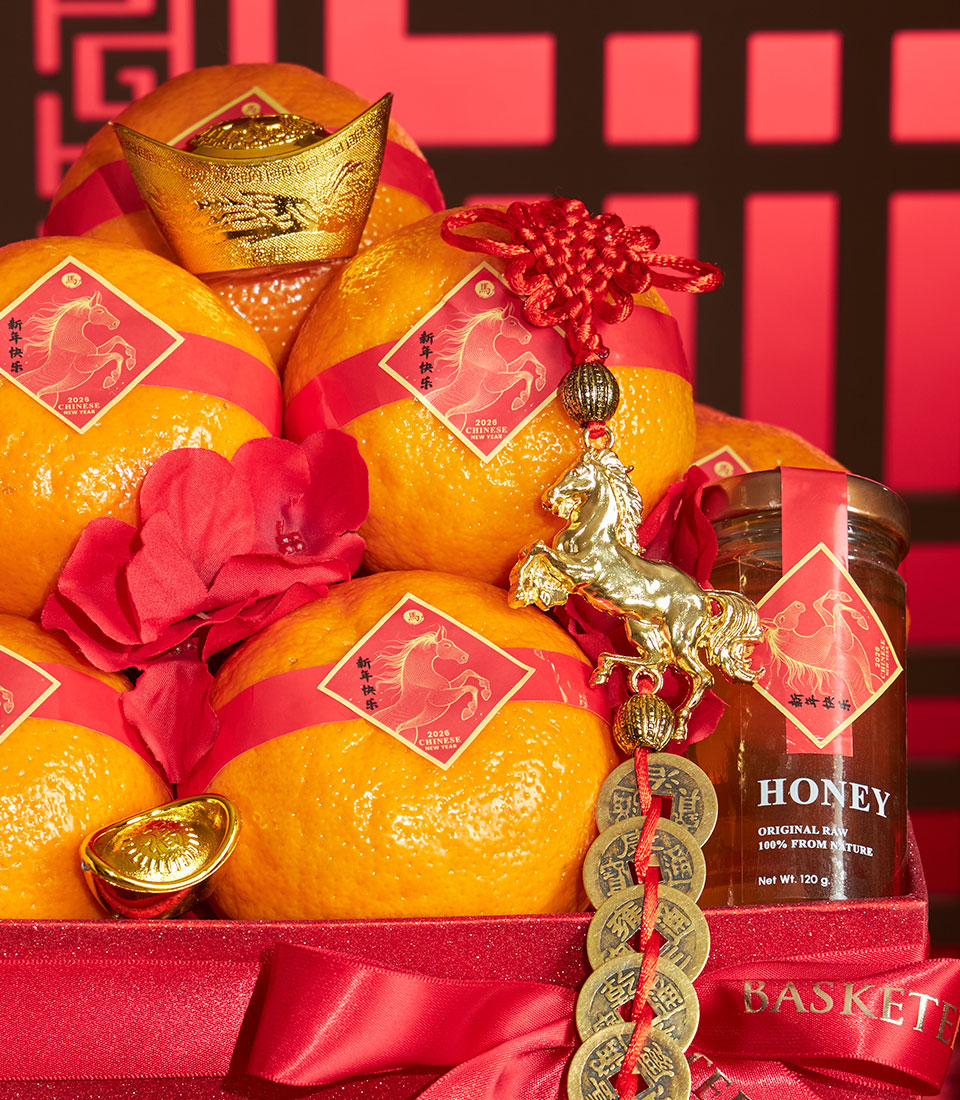 Festive Chinese New Year gift box with mandarin oranges, raw honey, gold coins and lucky charms in red glitter basket