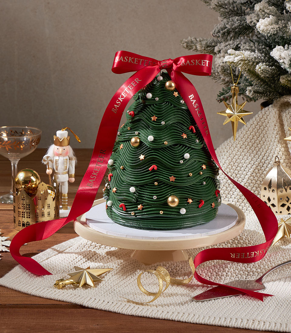 Charlotte Bakery Christmas tree cake: a festive artisan cake order in Bangkok. Dark green buttercream frosting, gold accents and red ribbon. Birthday cake delivery Bangkok.