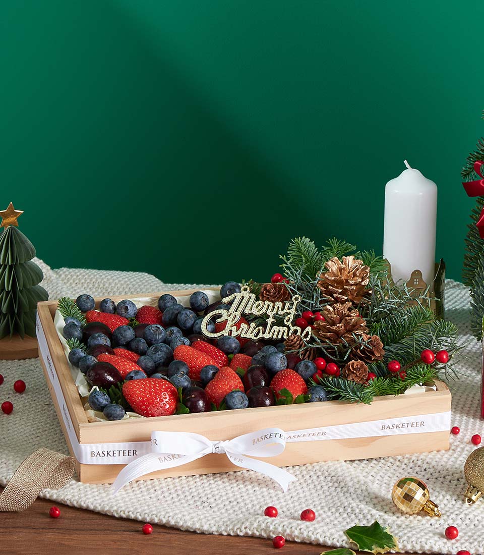 Festive berry fruit gift box with strawberries, blueberries, cherries, pine and golden pinecones for Christmas