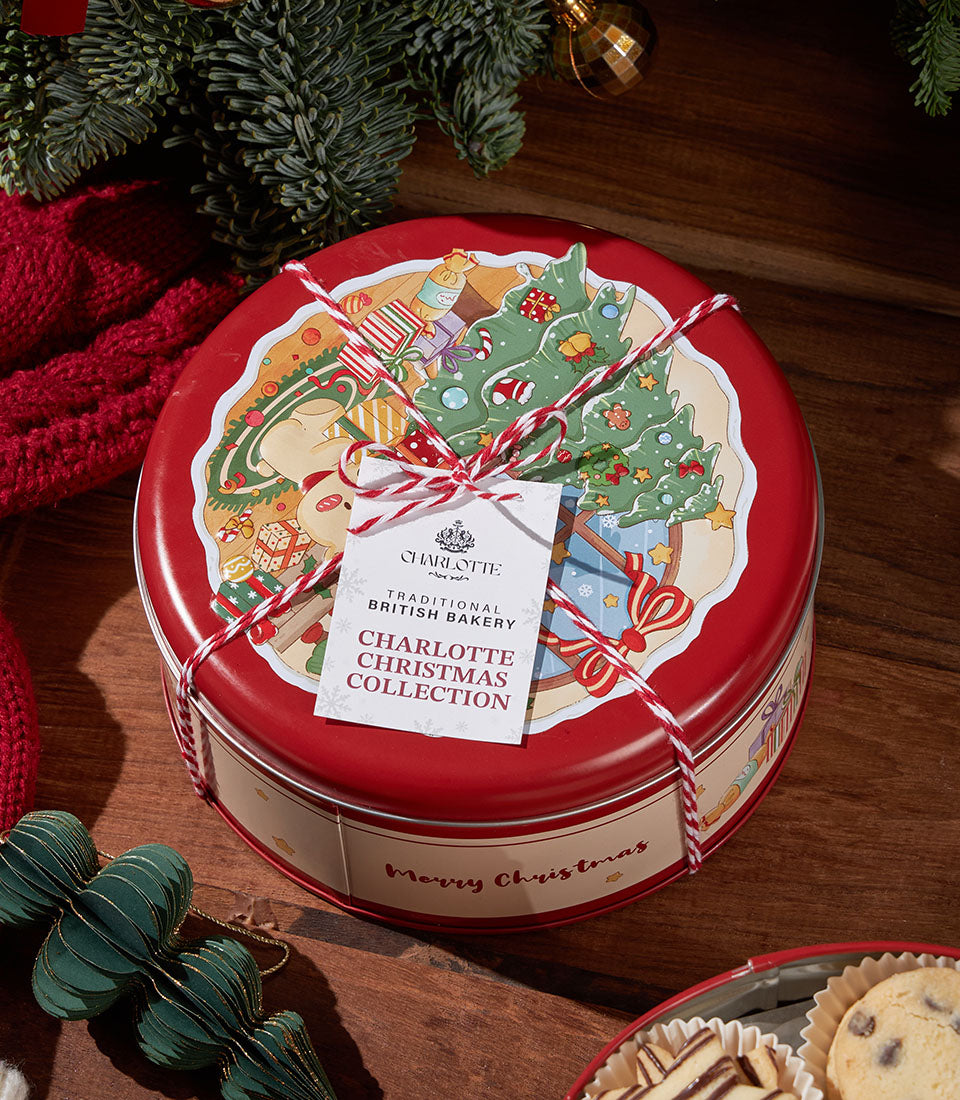 Festive red tin of traditional British Christmas biscuits with holiday illustration and gift tag on wooden surface