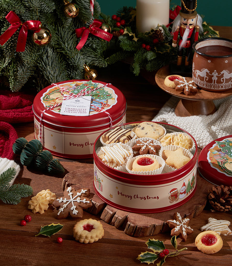 Red Christmas biscuit tins with assorted decorated cookies, gingerbread, and jam tarts in festive holiday gift set