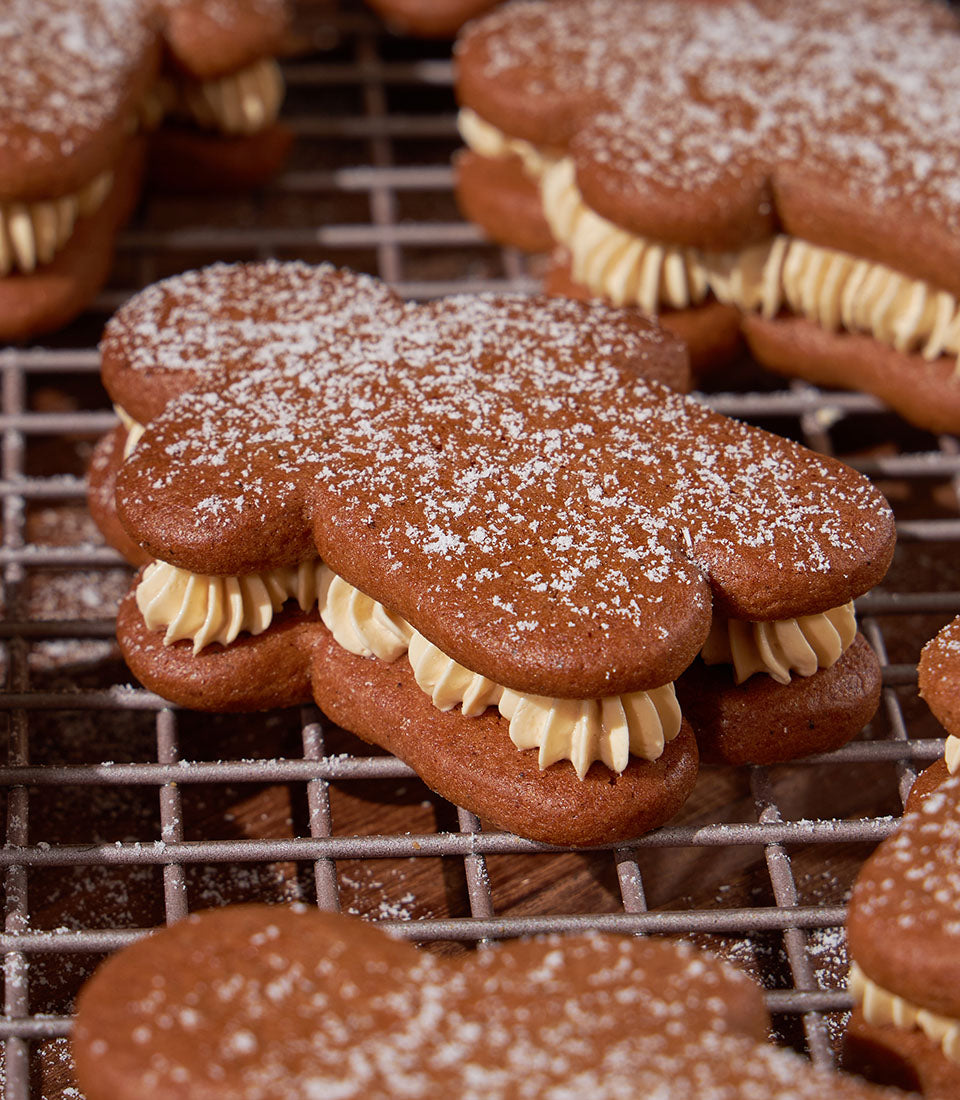 Cream-filled gingerbread men cookies with powdered sugar on cooling rack, Christmas bakery gift box set