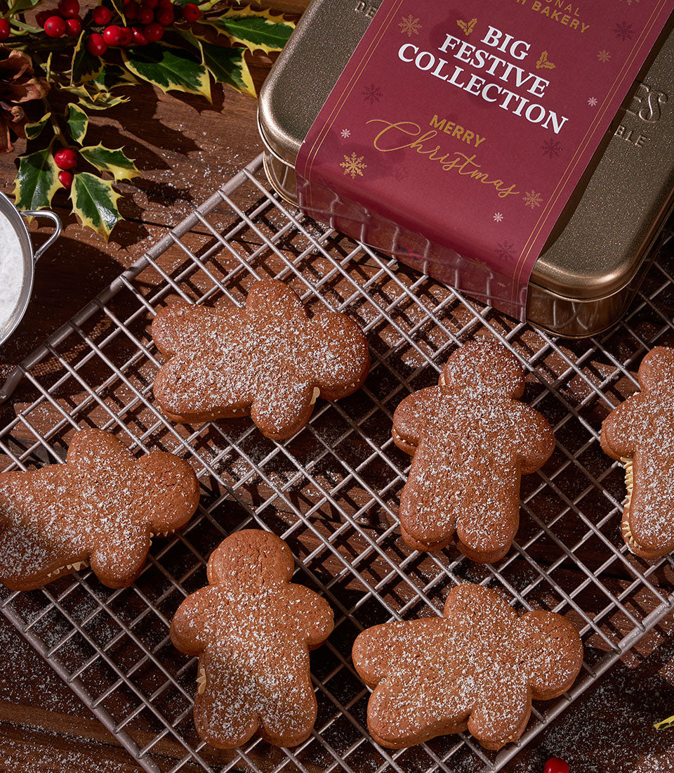 Cream-filled gingerbread men dusted with powdered sugar in festive Christmas tin with holly garnish