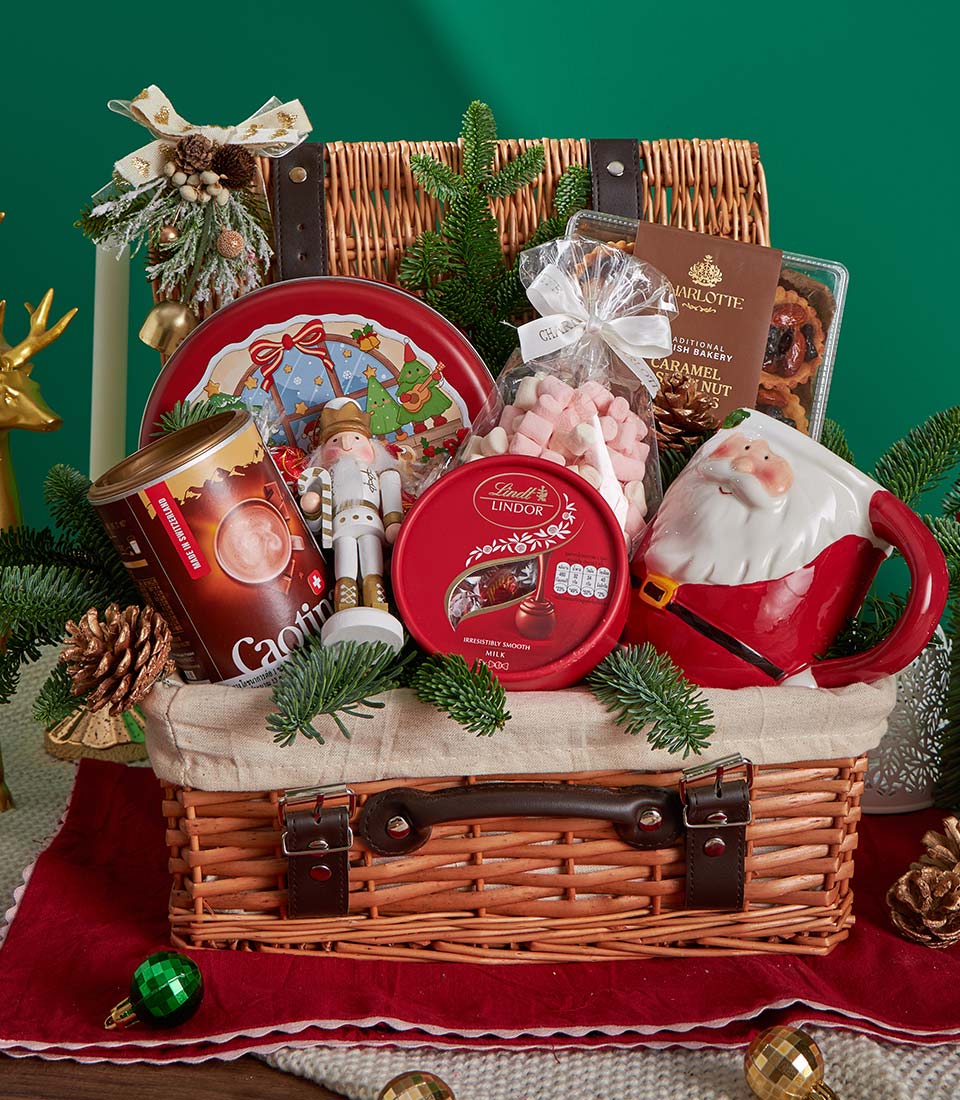Festive Christmas gift basket with gourmet chocolate, Swiss hot chocolate, biscuits and holiday treats in woven wicker with