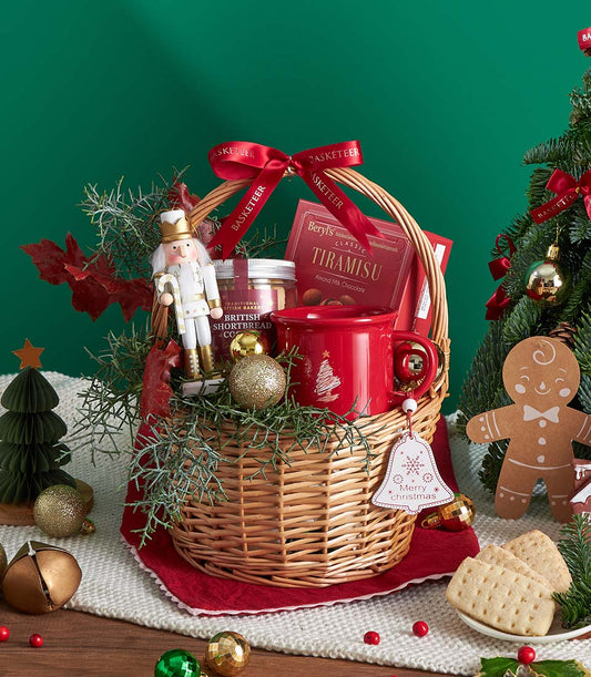 Wicker Christmas gift basket with gingerbread, chocolate, shortbread, festive mug, and gold baubles