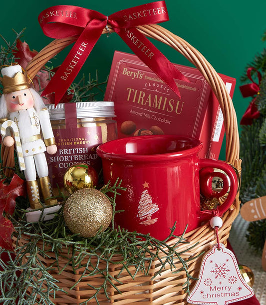 Wicker Christmas gift basket with gingerbread, chocolate, shortbread cookies, ceramic mug, and gold nutcracker