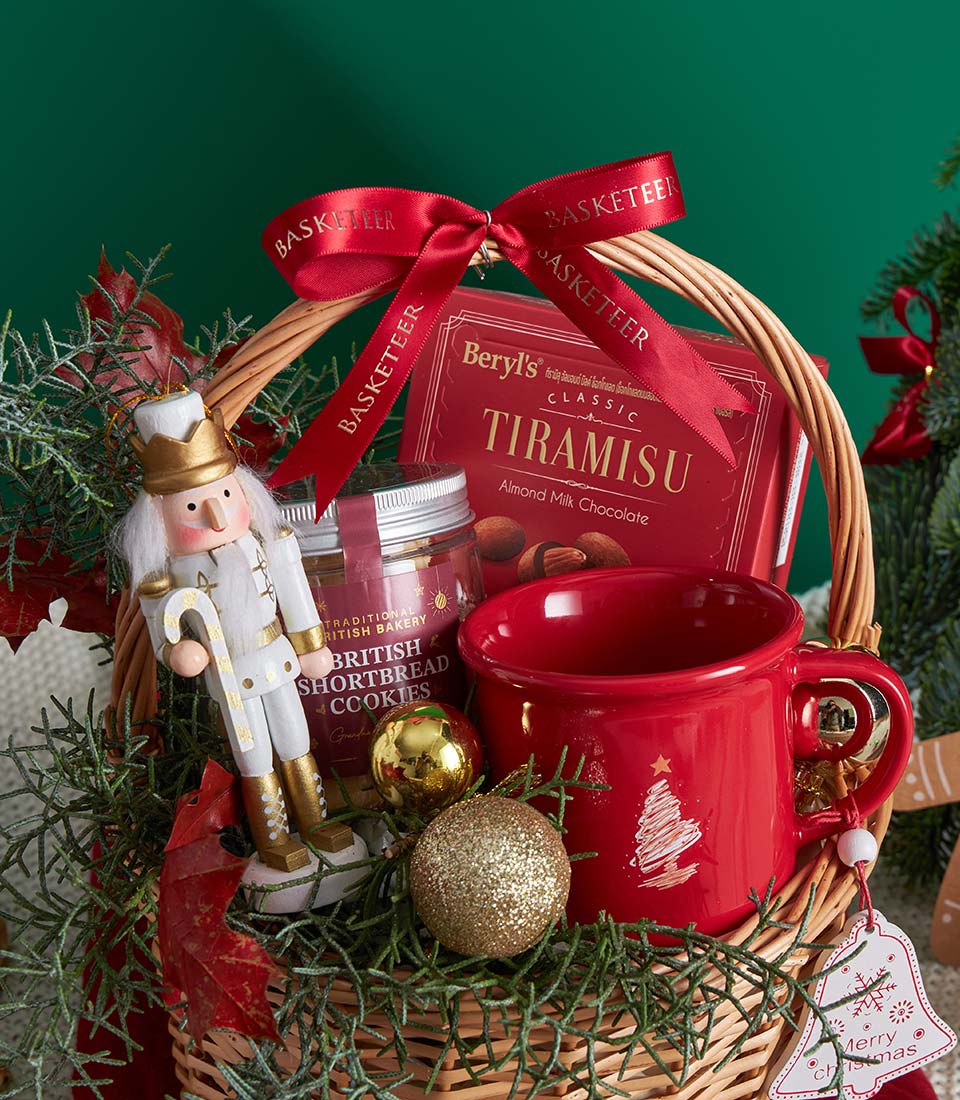 Festive wicker Christmas gift basket with gingerbread, chocolate, shortbread cookies, and holiday mug