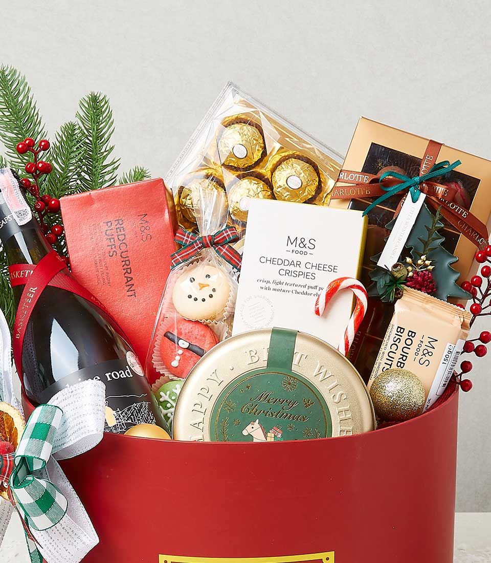 Festive red Christmas hamper with sparkling wine, gourmet chocolates, cheese crisps, and macarons