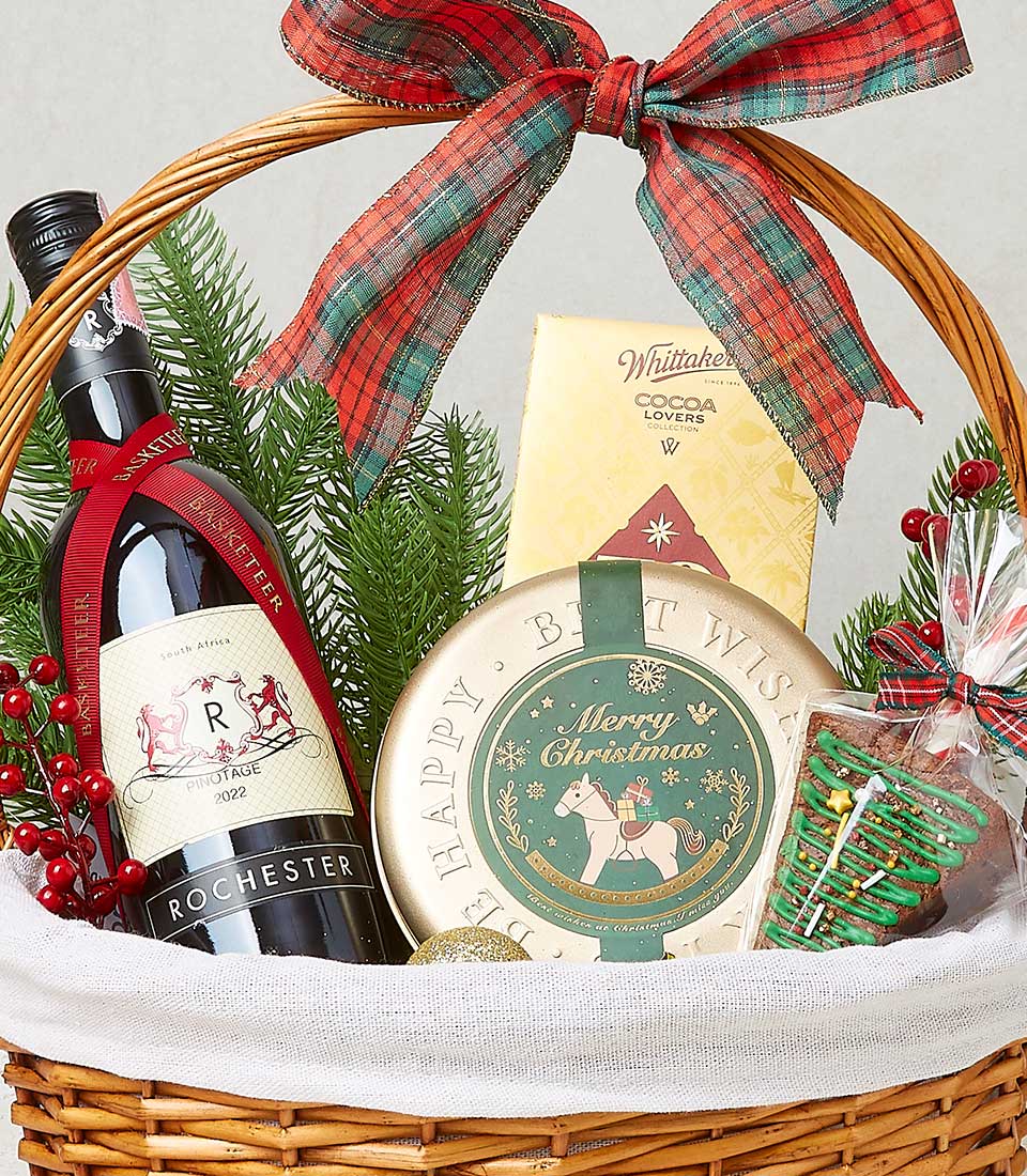 Woven wicker Christmas wine basket with red wine, Whittaker's chocolate, festive treats, and plaid ribbon bow