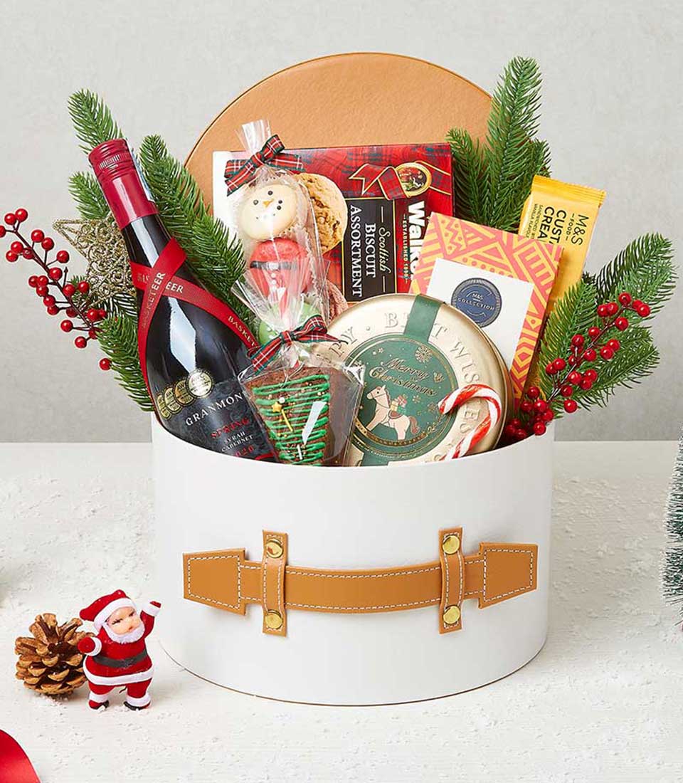 Festive Christmas wine gift box with red Syrah Cabernet, Scottish biscuits, and holiday treats in white cylindrical