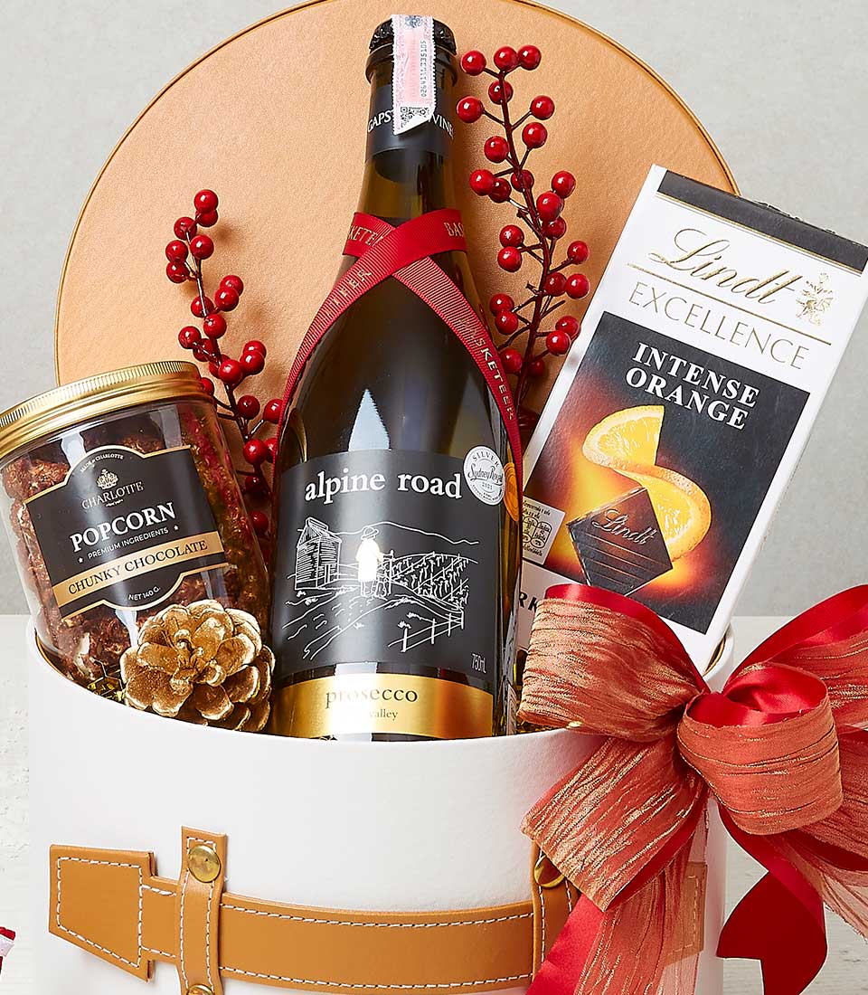 Yuletide Delights wine gift box with Prosecco, chocolate, and popcorn in white basket with red bow