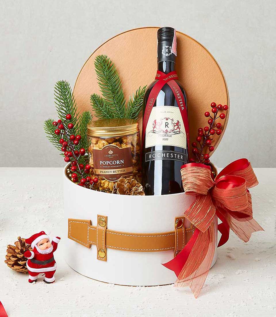Festive red wine and popcorn Christmas gift box with holiday greenery and gold-studded leather strap