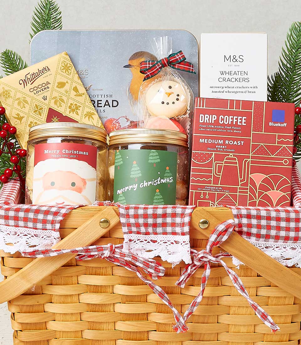 Woven wicker Christmas hamper with festive treats, red checkered liner, and holiday decorations