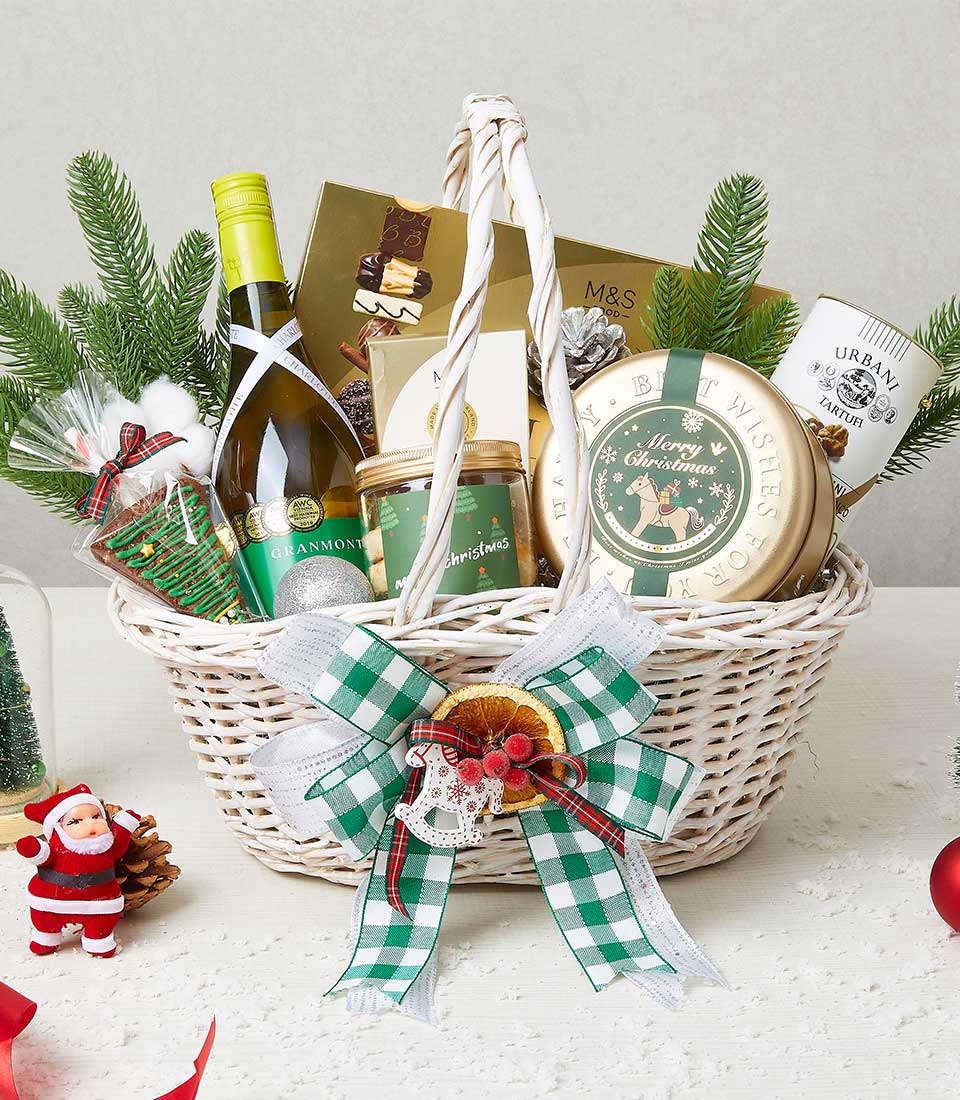 White wicker Christmas hamper with white wine, artisan chocolates, truffle selection, and festive treats tied with green