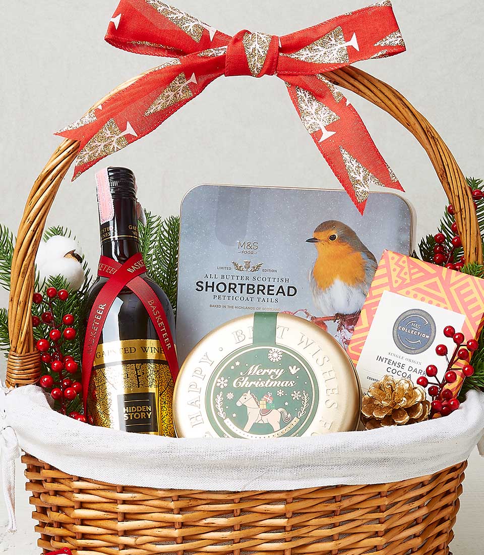 Woven wicker Christmas gift basket with Hidden Story red wine, Scottish shortbread, dark chocolate, and festive decorations
