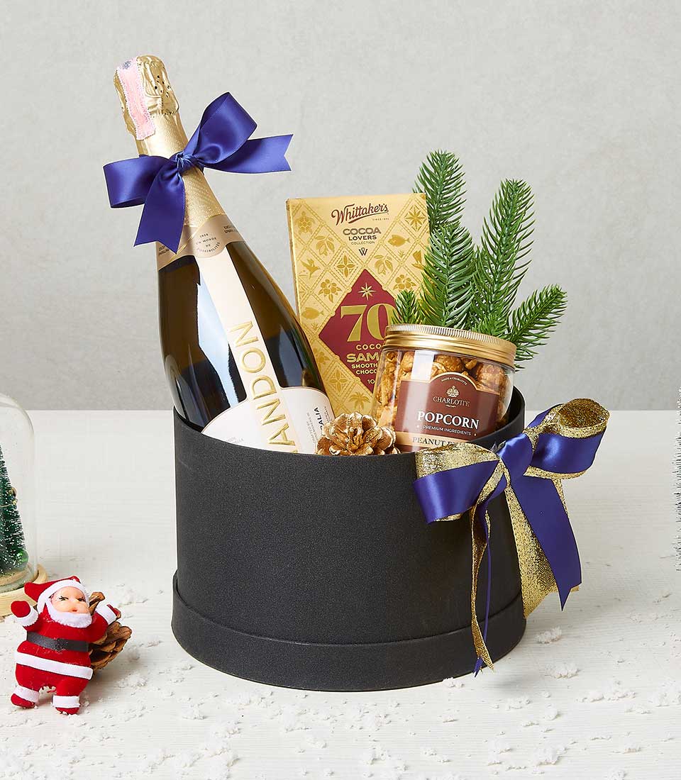 Festive black gift box with champagne, chocolates, popcorn, and gold accents for Christmas
