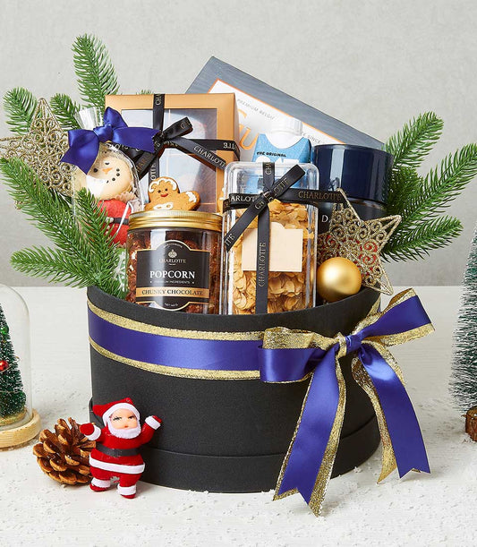 Luxury Christmas gift hamper with artisan popcorn, gingerbread, and festive treats in black cylindrical box with gold ribbon