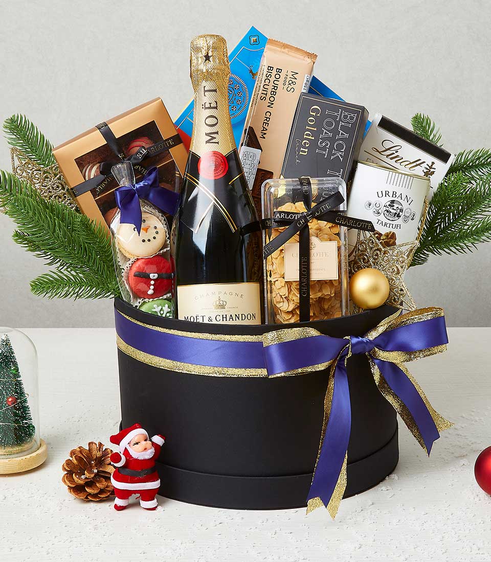 Luxury Christmas champagne gift hamper with macarons, chocolates, and truffles in black presentation box with gold ribbon