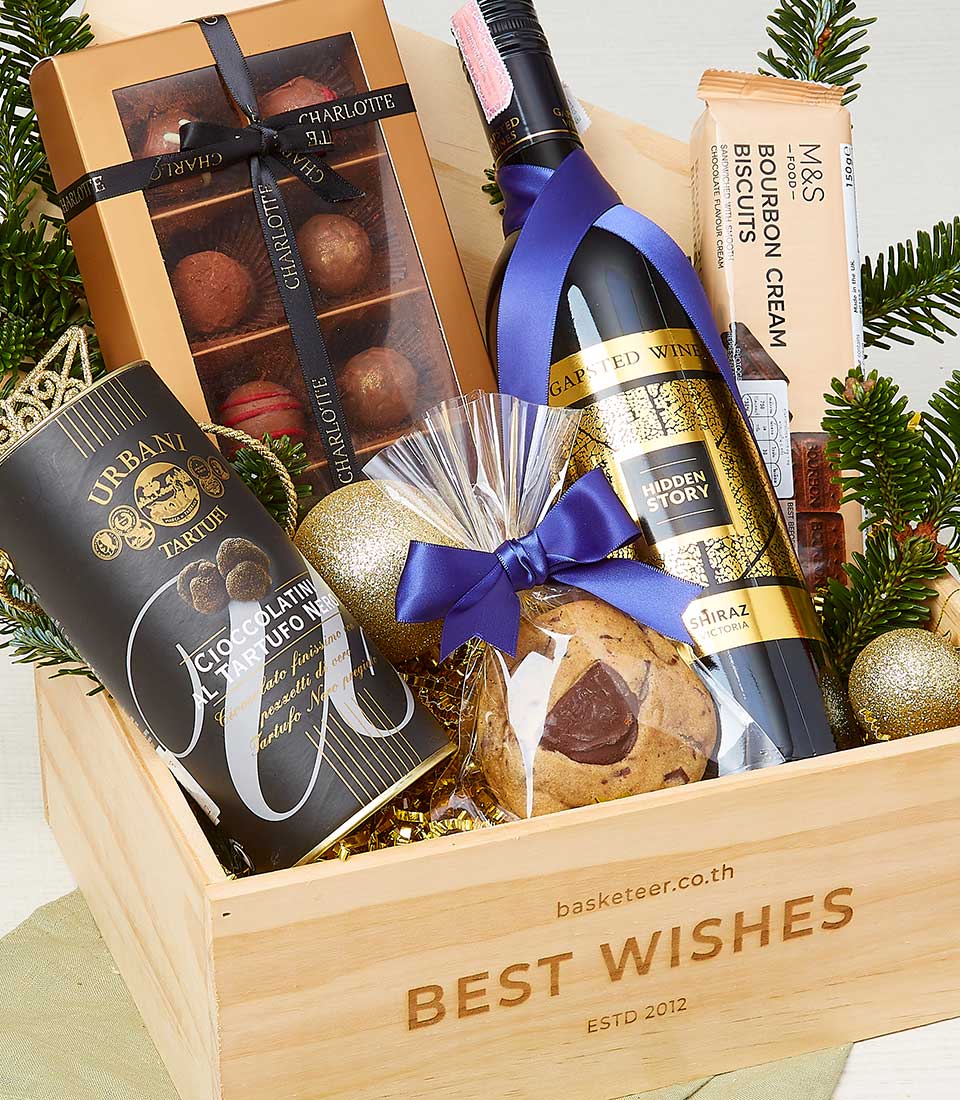 Festive Christmas wine and chocolates gift hamper in wooden crate with gold accents and holiday greenery