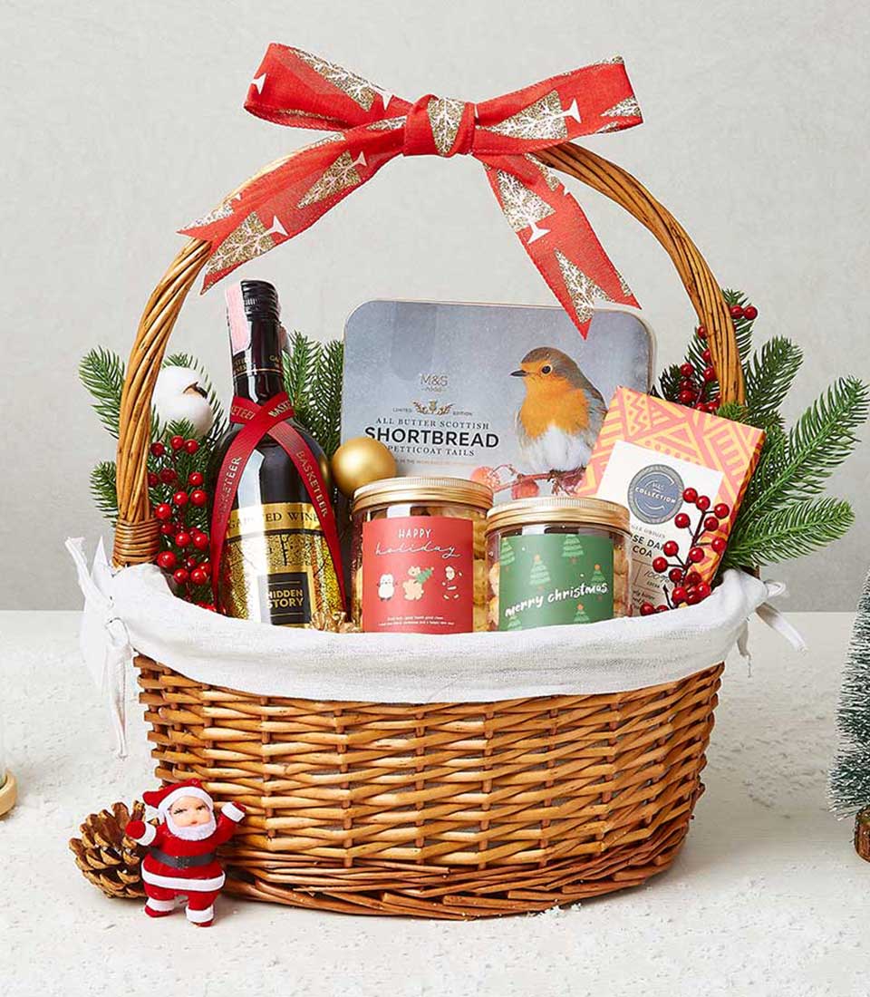 Wicker Christmas gift basket with red wine, Scottish shortbread, dark chocolate, and festive confections tied with gold