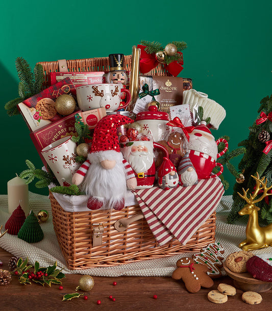 Festive Christmas gift basket with wicker weave, red reindeer mugs, gnome figurine, gingerbread cookies, and holiday ceramic
