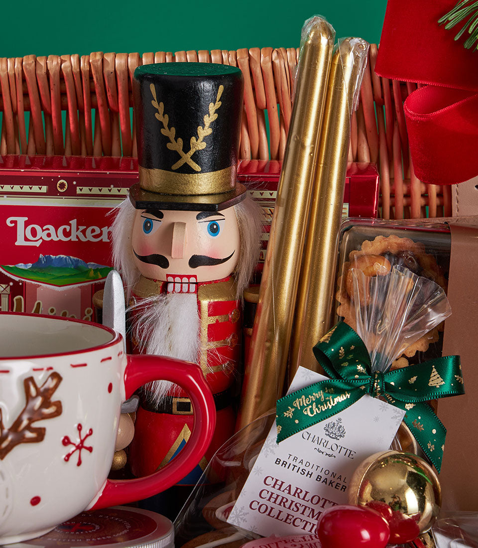 Grand festive Christmas hamper with nutcracker, golden candles, reindeer mug, and Charlotte Bakery baked goods in wicker