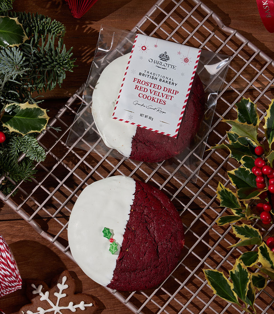 Red velvet cookies with white frosting drip and holly garnish, festive Christmas bakery gift
