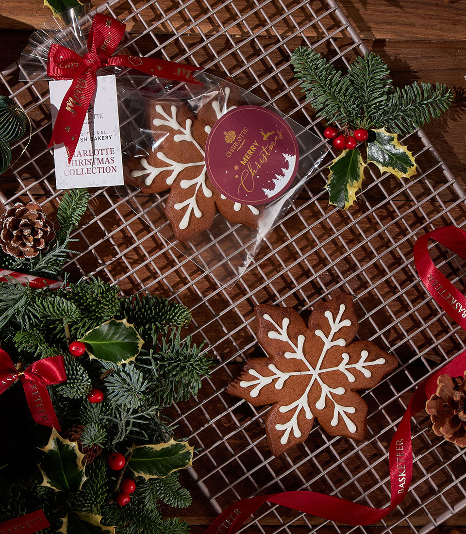 Snowflake gingerbread cookies with white icing detail, packaged in cellophane with red ribbon and festive Merry Christmas tag