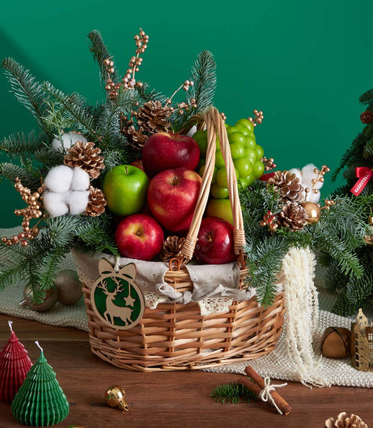Classic green pine Christmas fruit basket with red and green apples, grapes, and festive holiday decorations