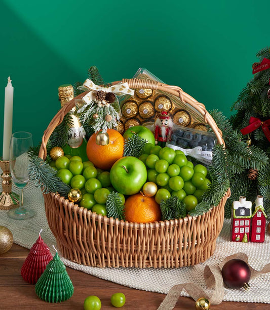 Festive wicker fruit basket with green grapes, apples, oranges, blueberries, chocolates, and wine for Christmas gifting